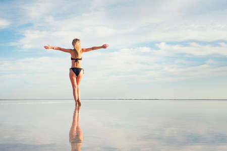 Beautiful woman on the beach, attractive slim model enjoying summer holidays. Sea, coast, woman and water reflection. copy space. girl sunbathing by the lake in the sun. The posture of joyの写真素材