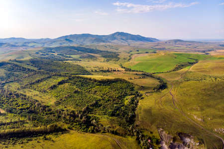 Autumn view. Hilly terrain. Yellow slopes and trees contrast with green fields. Top view of the field in Altai.の写真素材