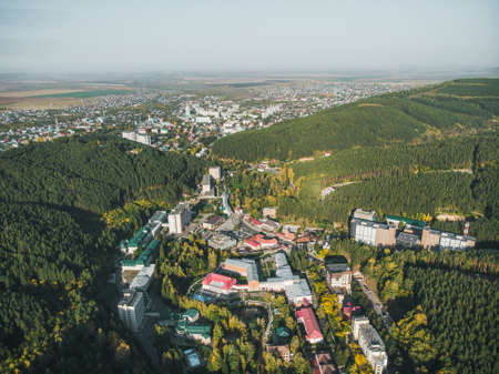 Top view of the resort town Belokurikha. Bird's-eye view of the houses among the forests on the slopes of the mountains. Aerial view of a small town in the Altai territoryの写真素材