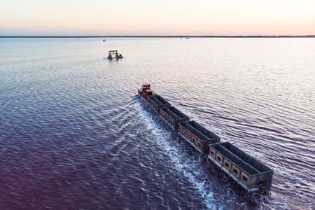 Awesome train rides on the rail in the water with white salt on the background of beautiful blue sky. aerial view, view from the topの写真素材