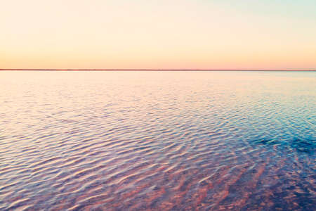 Beautiful yellow pink sunset over lake. The straight line of the horizon. Rose water in a salt lake.の写真素材