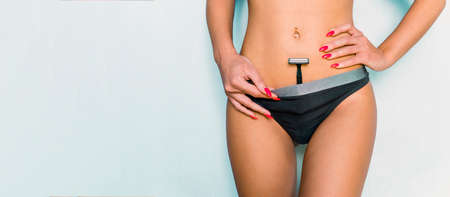 Beautiful, slim woman shaving crotch, on blue background. shaving machine in panties. girl health and intimate hygiene. copy space for text and advertising. hair removalの写真素材
