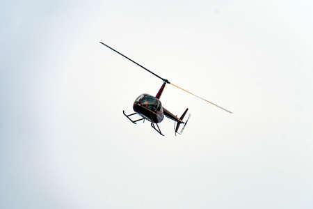 A small red helicopter flying in the skyの写真素材