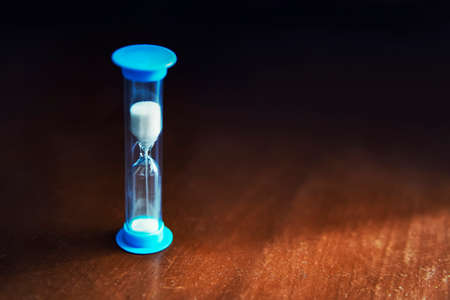 Hourglass blue color with white sand on dark backgroundの写真素材