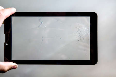 broken tablet screen. Cracks on the glass of the tablet computer in the hands of men.の写真素材