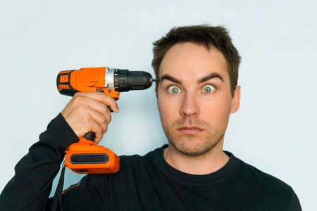out of my mind. male Builder drills his brains out. Crazy guy with a stupid face. Fatigue from hard work. Inadequate customer. portrait of psychopath close upの写真素材