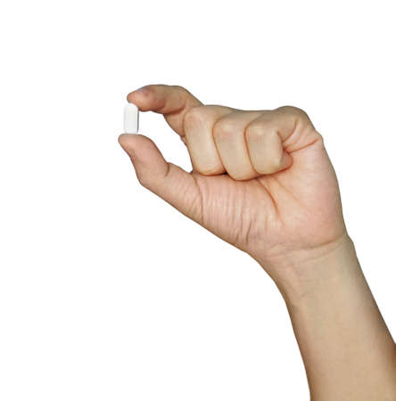 Hand holding a pill between thumb and forefinger isolated on white background. white pill in his hand.の写真素材