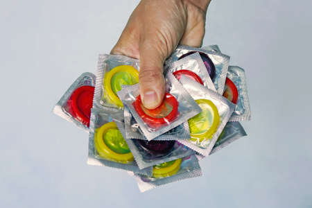 a large number of colorful condoms in a man's hand.Safe sex concept. Hand with condomの写真素材