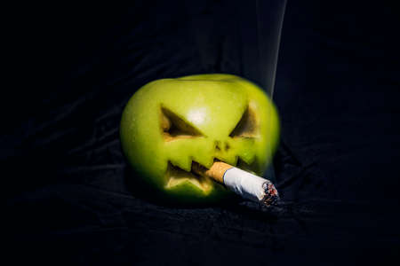 concept of harm to health from Smoking. An evil Apple with a cigarette in its mouth.の写真素材