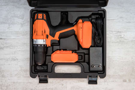 Top view of electric screwdriver on white background. orange screwdriver or drill in a black container lies on the floor. Tool for tightening screws. screw gunの写真素材