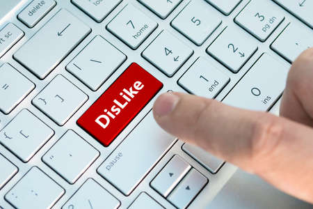 dislike on keyboard button. A male finger presses a color button on a gray silver keyboard of a modern laptop. Button with inscription close up.s.の写真素材