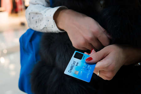 Close up of woman's hands holding credit card. Lady is paying using bank card, shopping and retail...