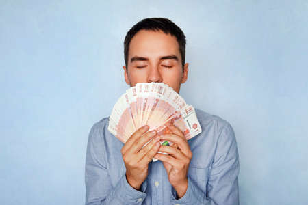 business, people and finances concept - businessman smelling Russian money. The sweet smell of...