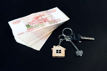 Banknotes of Russian rubles and keys to the apartment on the black table. Estate sale. The deal for the sale of the apartment. Concept.の写真素材