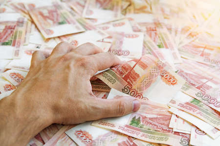 Lust for money. Large stack of banknotes, Russian rubles, banknotes 5000 rubles. hands are grabbing money.の写真素材