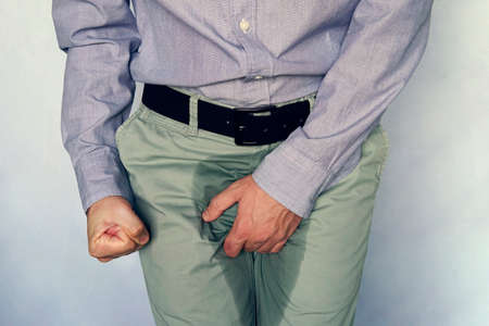 men are scratching penis against blue gray background. People itching crotch. Human body problem or healthcare and medicine concept. incontinence and wet pantsの写真素材