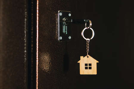 House key with house model keychain in door. process of opening the front door to the apartment.の写真素材