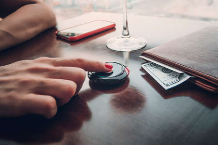 Close-up Of Woman's Hand Ringing Service Bell,Buzzer in the restaurant and female fingers. Call salesperson close up. Button to call the waiter in restaurant. Tip's on the Desk in the folder.の写真素材