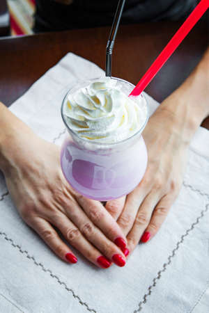 woman holding a glass of beautiful milkshake in a restaurant on the tableの写真素材