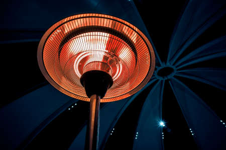 Infrared heater round shape on a black background in a large cold room. heating at nightの写真素材