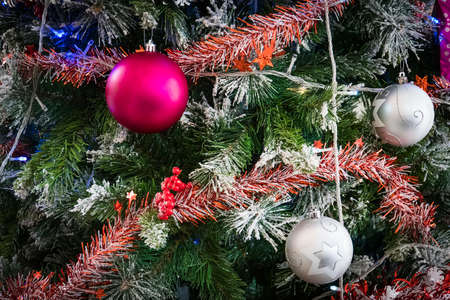 Closeup of Green Christmas tree and pink ball decorations. Colorful balls and garlands on a fir branch.の写真素材