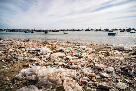 View on a sandy beach near to fishing village with a lot of garbage. Pollution of a coastline. Mui Ne, Vietnamの写真素材
