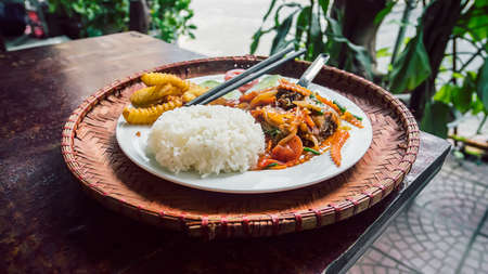 Japanese curry rice with vegetables, seafood meat, carrot and potato on wooden table. Asian cuisine in an outdoor restaurantの写真素材