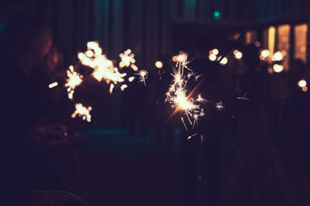 Bengal light at the blurred background of people's shadows with sparklers. Indoor firework by the turned off light. Indoor celebration with bengal lights burning. Beautiful play of lights and darks.の写真素材
