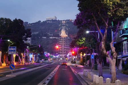Scenic night view of the bahai temple and bahai gardens from the central street in Haifa, Israel. Deserted night road and red traffic light at background of beautiful slope of Mount Carmelの写真素材