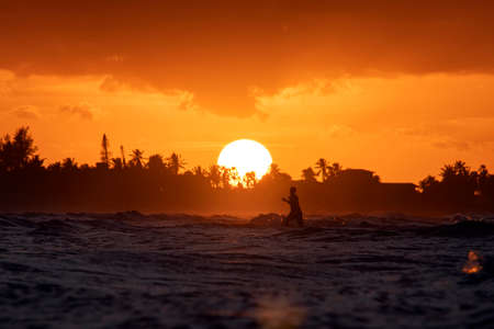 people beach sea sunset concept. young joyful, happy male tourist runs along the beach. Silhouette of a tourist against a beautiful sunset on a tropical island. The waves of the sea in the foreground.の写真素材
