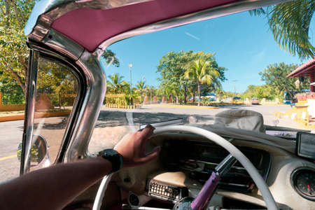 Inside of a vintage pink classic american car in Cuba. driver holds the steering wheel of the old car with his hand. Varaderoの写真素材