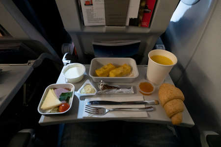 A variety of food on the folding table on the plane. Late dinner during the flight at night.の写真素材