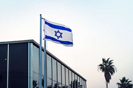 View of the Israeli flag in the streets of Tel Aviv in the afternoon. flag of Israel flutters in the...