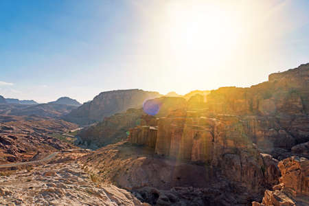 sun is shining brightly over red rocks in the Jordan desert, near the city of Petra.