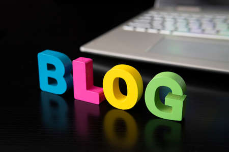 The word blog on a black table against a gray laptop. The concept of video blogging development in the world.の写真素材