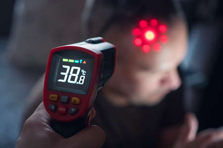 Non-contact digital infrared thermometer in the hands. Monitoring and measuring the temperature of colds and flu. Cold season concept.の写真素材