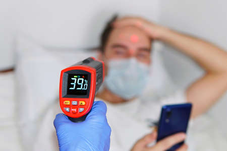 A male person being measured body temperature with a contactless thermometer. A patient in a...