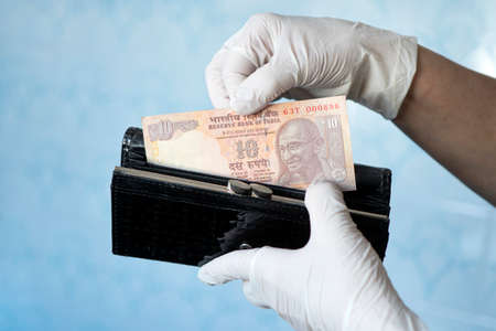 woman taking money out of female wallet wearing rubber gloves to prevent the spread of bacterias or viruses, take shopping during coronavirus pandemic. Microbes on money. Refusal of cash.の写真素材