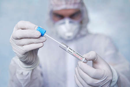 COVID-19. Coronavirus swab sample COVID-19. swab coronavirus test. Epidemic outbreak. a man in a chemical protection suit holds a test tube for analysis.の写真素材