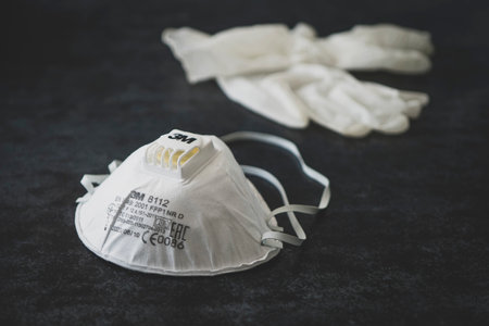 Surgical gloves made of latex, and medical protective mask, in disorder lie on a dark background. April 14, 2020. Barnaul Russia.のeditorial素材