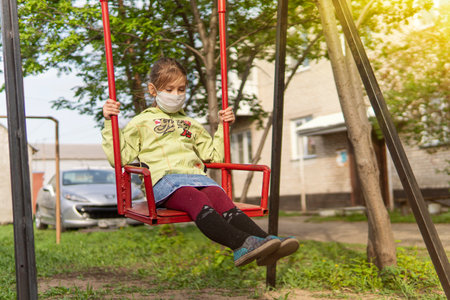 Unhappy children playing with face masks on playground during quarantine covid 19. Easing of quarantine restrictions, the ability to go outside. Russia. Barnaul. May 1, 2020のeditorial素材