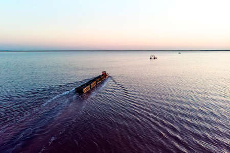 Old train rides on the railway laid in the water through the salt lake. train travels from water. Mined salt in Lake Burlin. Altai. Russia. Bursolith. aerial view, view from the topの写真素材