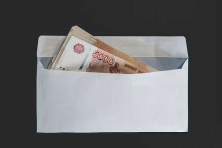 Large denominations of 5000 rubles in a white envelope. A man hand holds an envelope with money. the concept of bribery and corruptionの写真素材