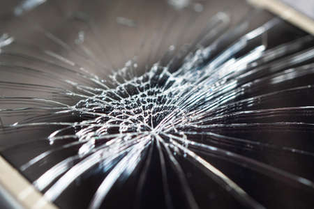 Smartphone with broken screen on dark background. close up