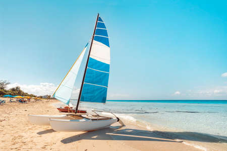 A sailing catamaran is parked on the white sand on the seashore against the backdrop of beautiful tropical nature. tourist attractions in Cuba.の写真素材