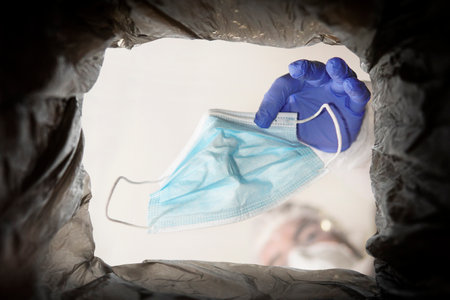 Throwing away single use medical face mask. Face mask after use. Environmental pollution by medical...