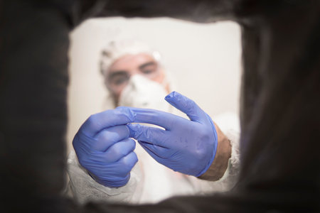 Closeup cropped portrait, healthcare professional throwing away blue disposable latex gloves in trash. Infection control protocol.の写真素材