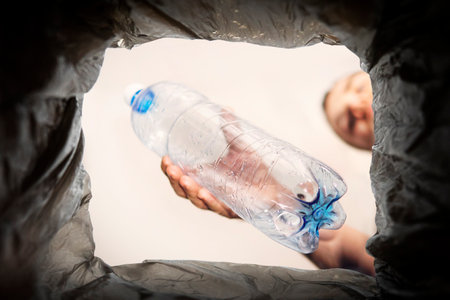 Plastic bottle waste, for recycling. Concept of the problem of plastic waste disposal. A man throws an old used bottle into a black trash canの写真素材