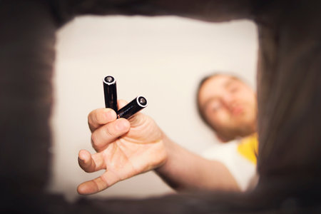 Ecology recycling concept, few used batteries in hand drop them in garbage bin, alkaline batteries ban on disposing, trash bin for recycle accumulatorの写真素材