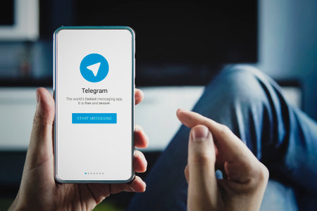 Man holding smartphone with Telegram logo with the finger on the screenのeditorial素材